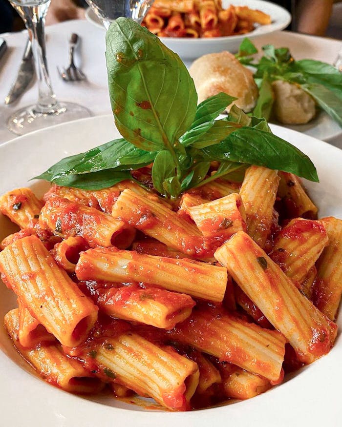 team-01 Close-up of a flavorful rigatoni dish with basil and tomato sauce served in a Paris restaurant.